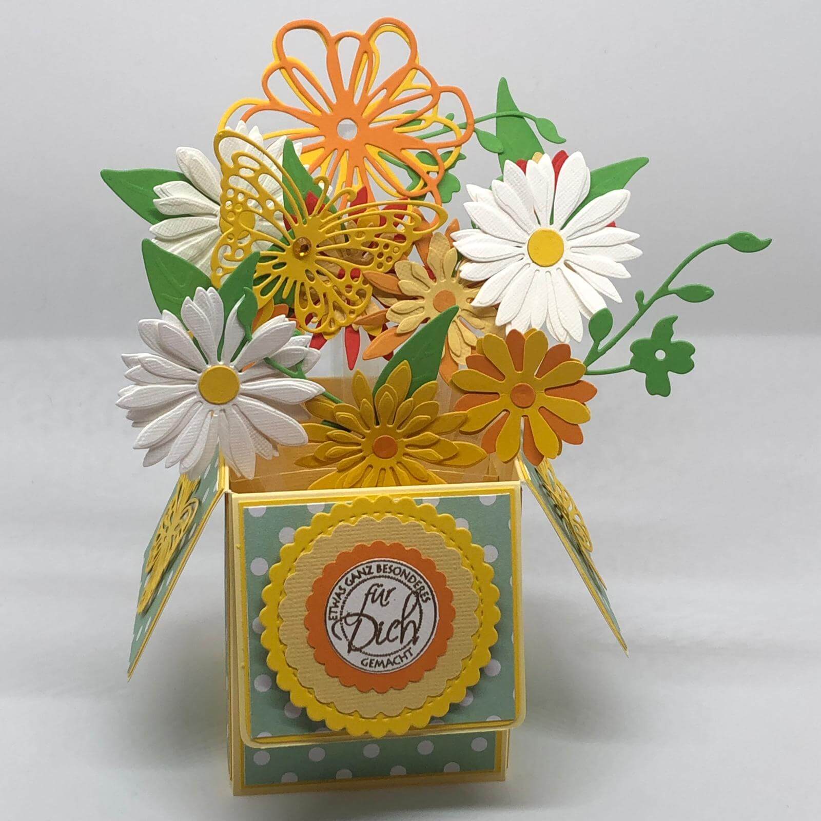 Aufklappbare Papierbox voller gelber, oranger und weisser Papierblumen mit dem Schriftzug Für Dich