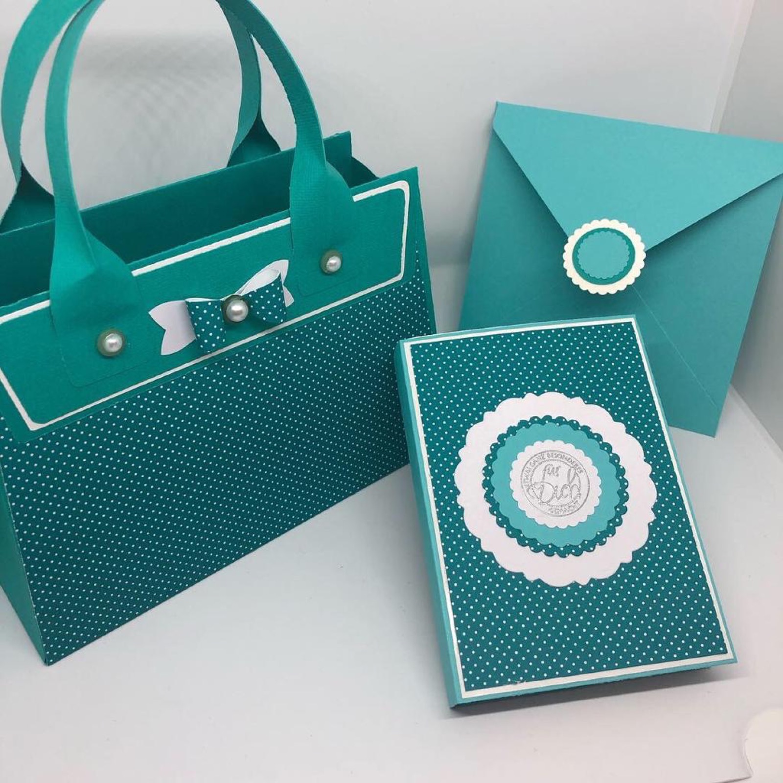 Petrolfarbene Papiertasche, Schachtel und Kuvert mit runden weissen Siegeln