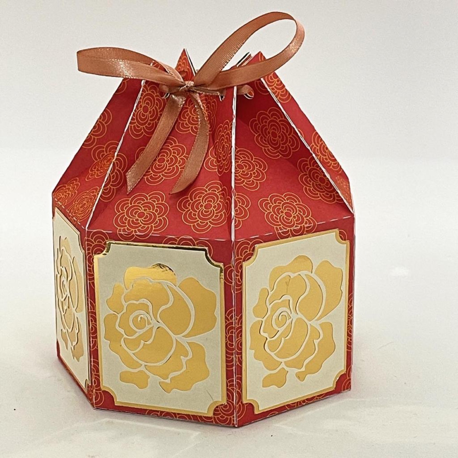Rot-goldene Laternenbox mit Rosenmuster und einer Satinschleife obenauf