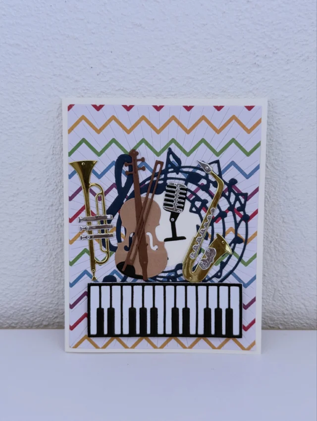 Grusskarte mit buntem Zickzackmuster, Papier-Instrumenten und einer Klaviertastatur