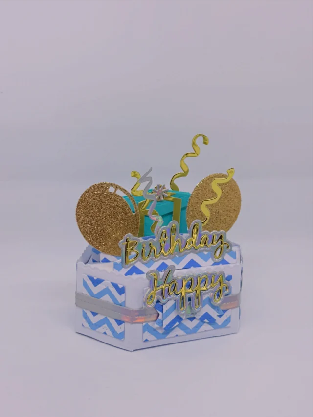 Kleine hellblaue Geburtstagsbox mit goldenem Happy-Birthday-Schriftzug, Ballons und Konfetti aus Papier