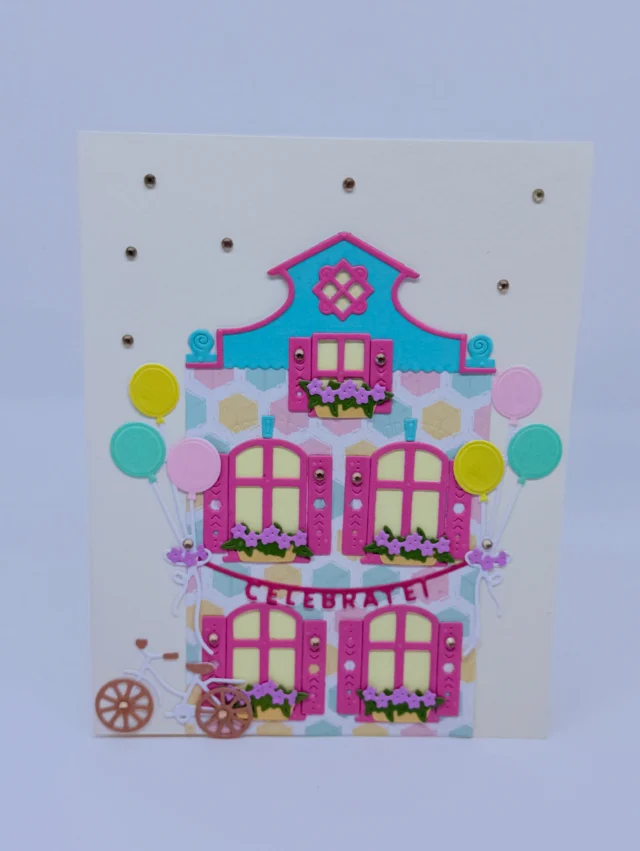 Karte mit einem pink-türkisen Papierhaus, Balkonen, Blumen und bunten Punkten