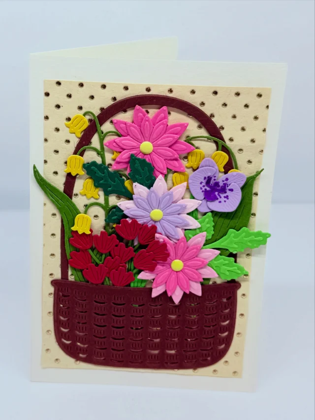 Karte mit einem randvoll gefüllten Blumenkorb aus buntem Papier auf getupftem Hintergrund