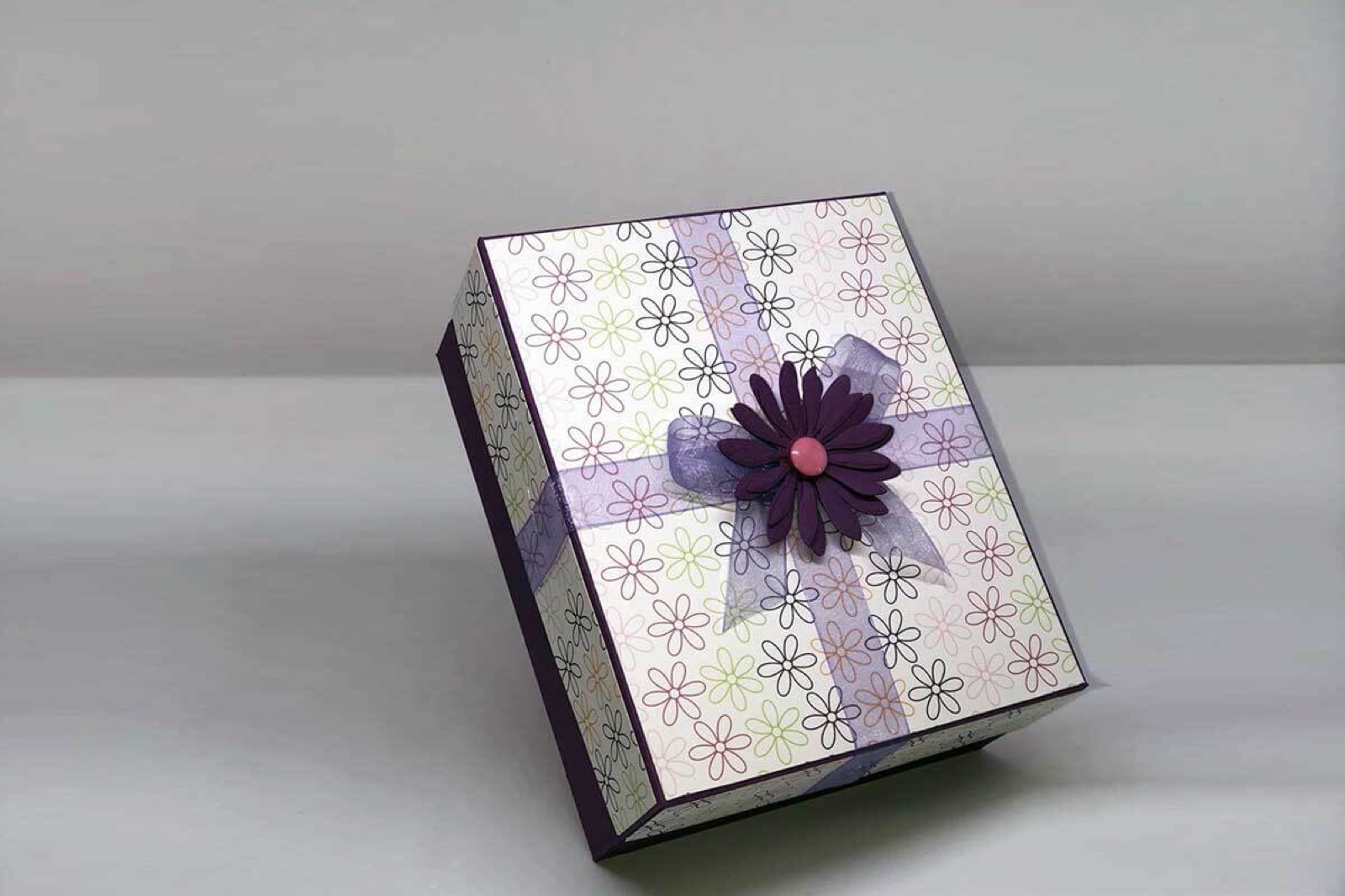 Box in Violett- und Grautönen mit gemustertem Deckel und Papierblüte