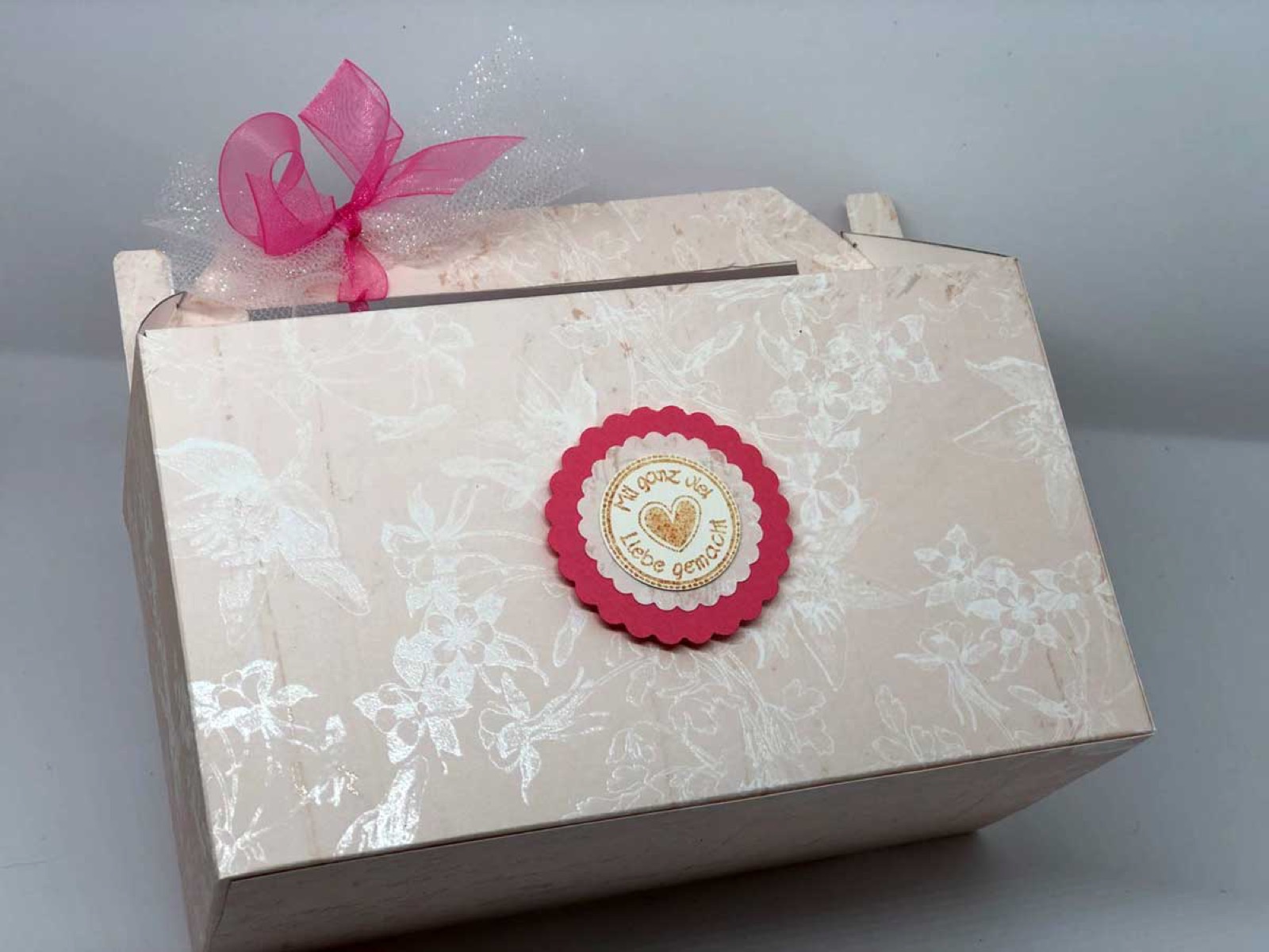 Cremefarbene Box mit Schneeflockenmuster und pinker Schleife von der Seite
