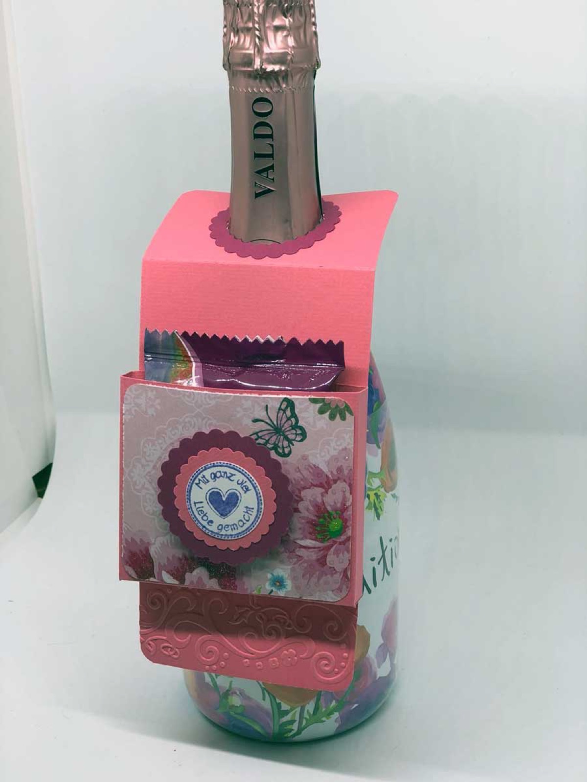 Proseccoflasche in einer bunten Papiermanschette mit rundem Anhänger