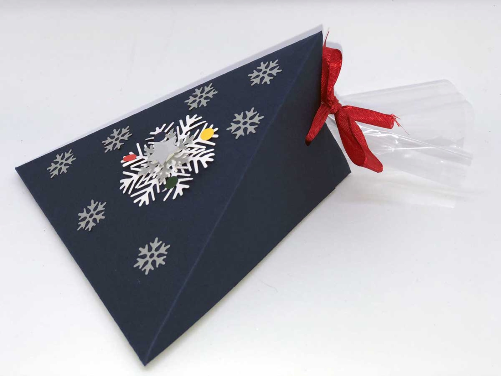 Dunkelblaue Dreiecksbox mit weissen Schneeflocken und roter Schleife
