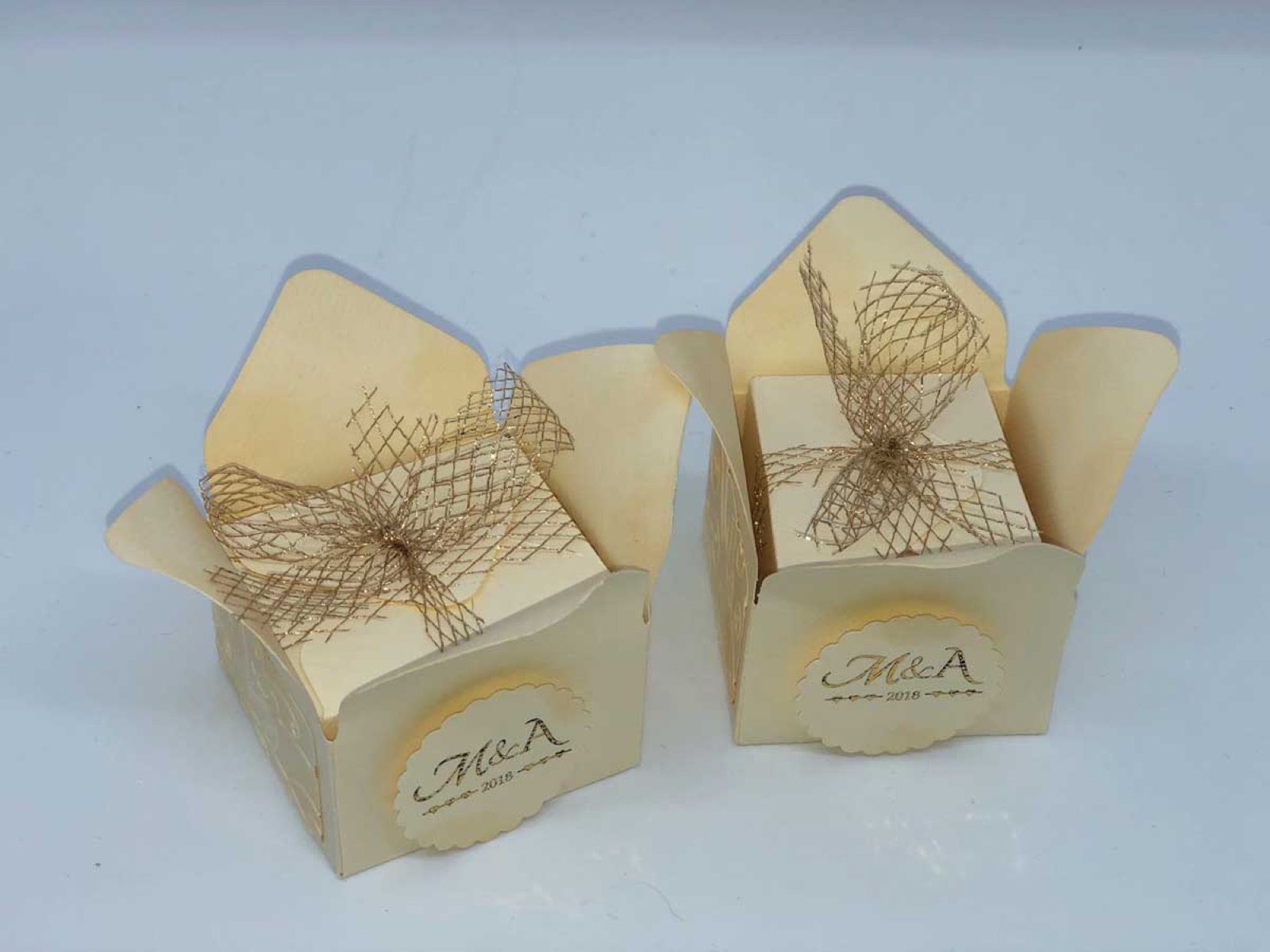 Zwei cremefarbene Boxen mit Schleife und aufgedrucktem Logo von vorne