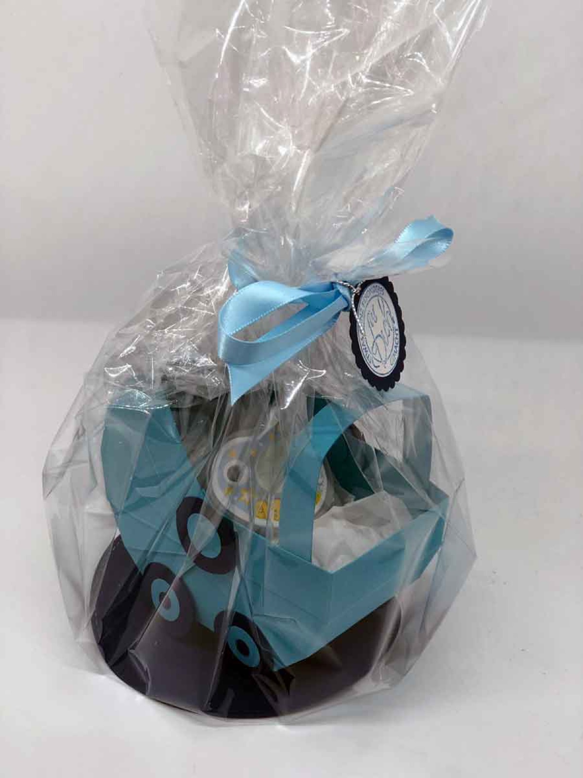 In Klarsichtfolie verpacktes Babygeschenk mit blauem Band und Nuggi