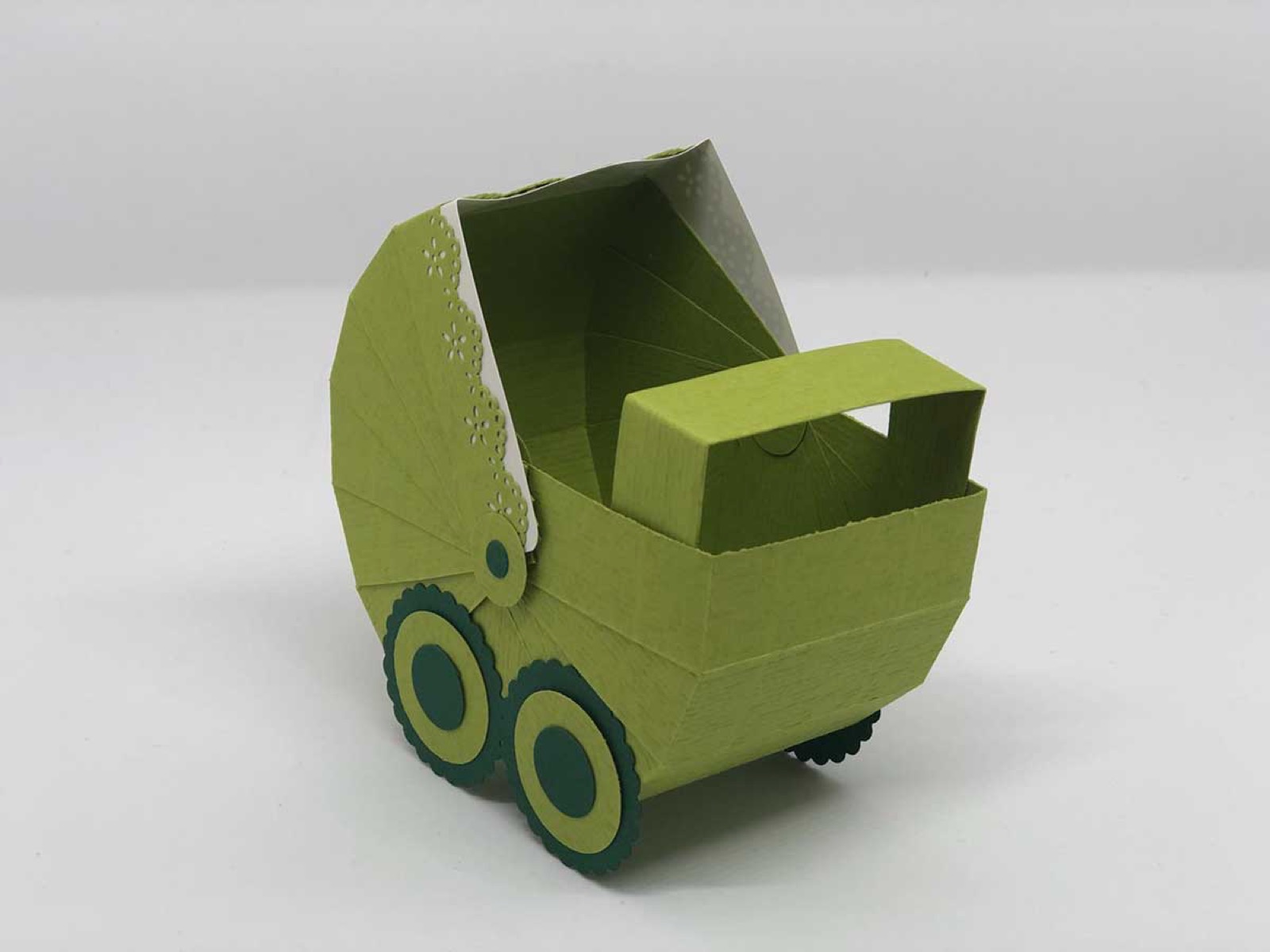 Kinderwagen aus grünem Papier von schräg oben