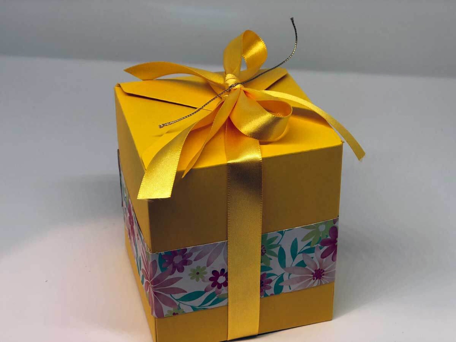 Gelbe Box mit goldener Schleife von schräg vorne