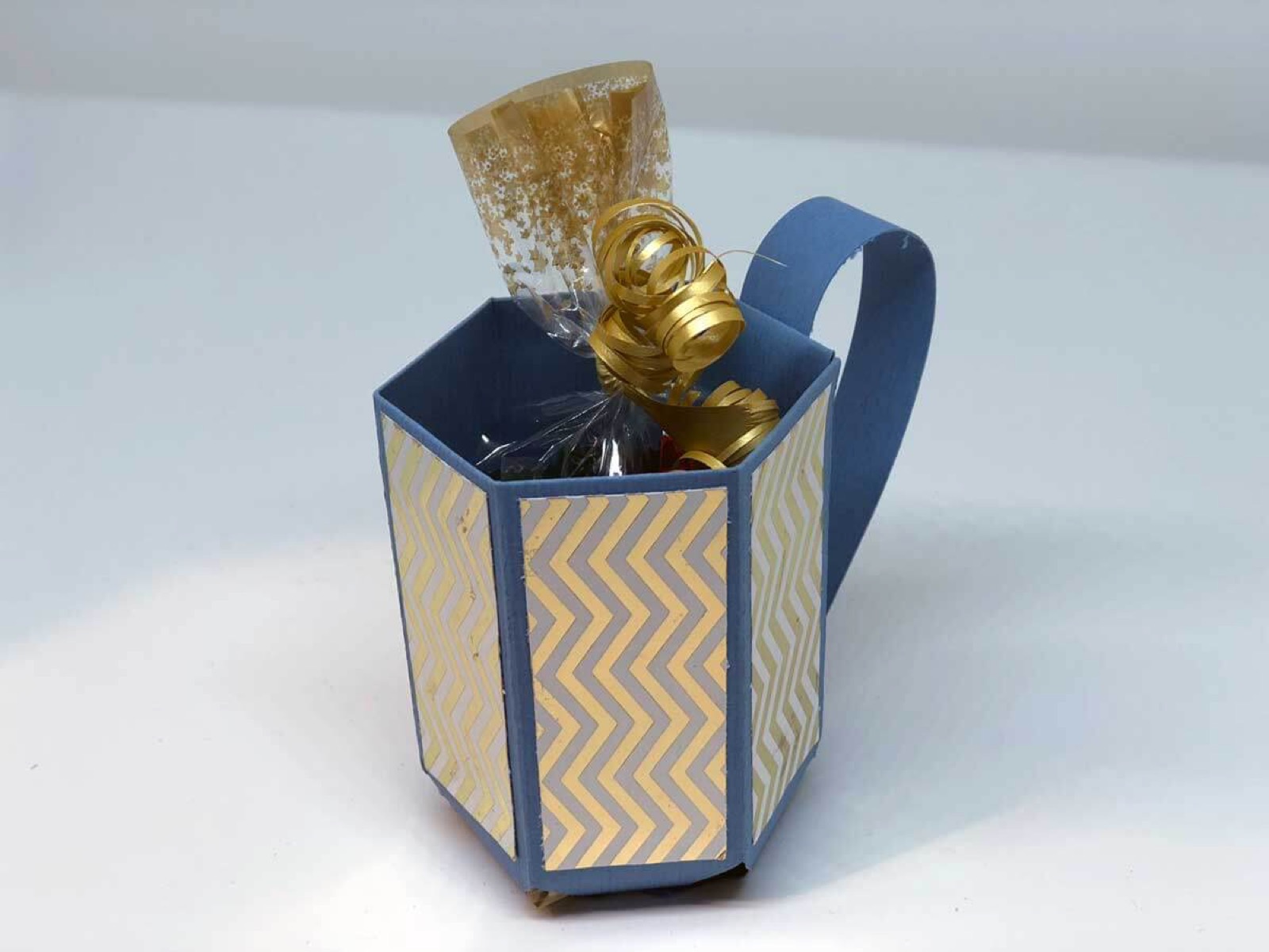 Box in Form einer Tasse aus blauem Zickzackpapier, gefüllt mit Pralinen