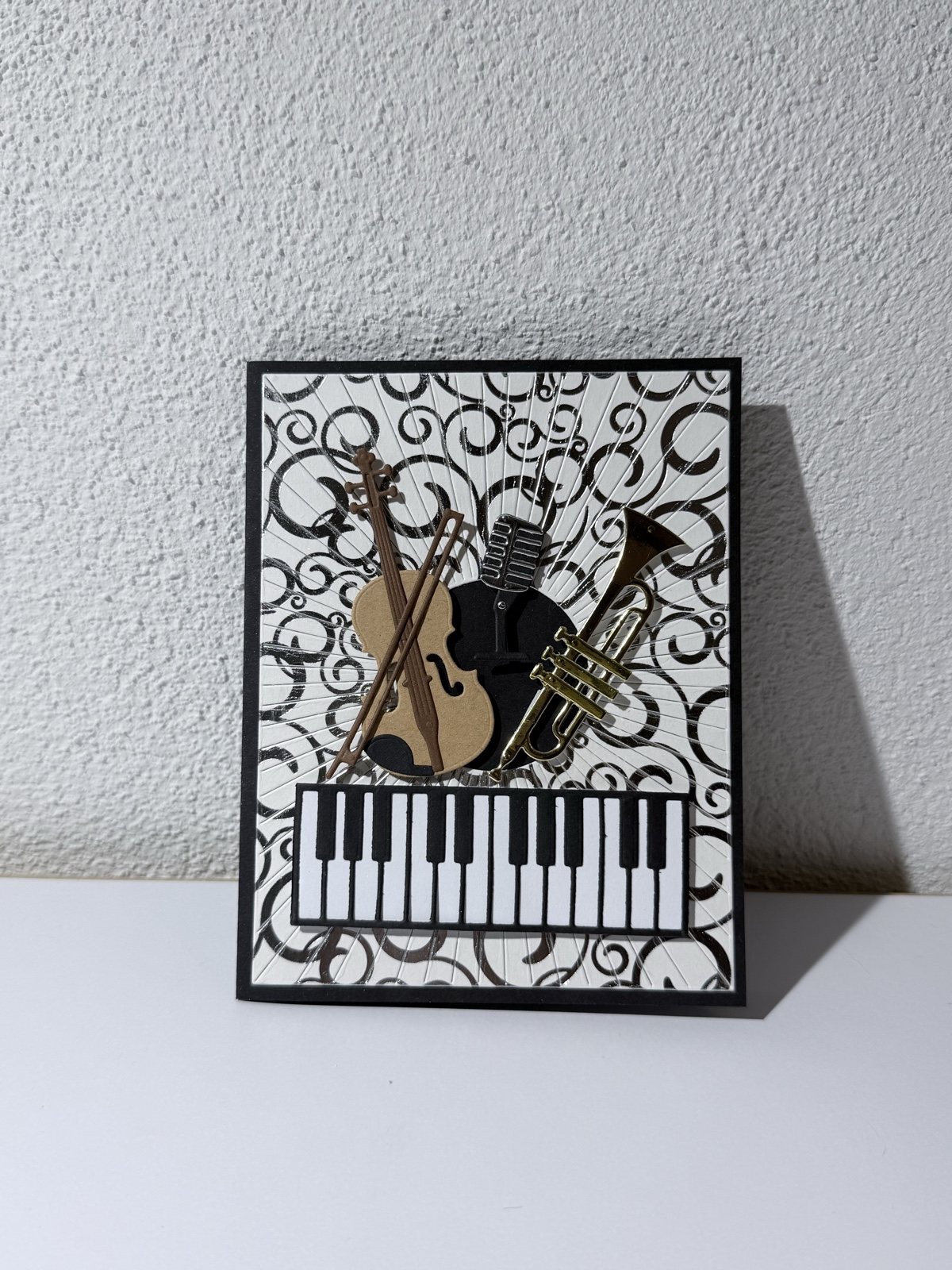 Schwarz-silberne Karte mit Geige, Mikrofon, Trompete und Klaviatur aus Papier